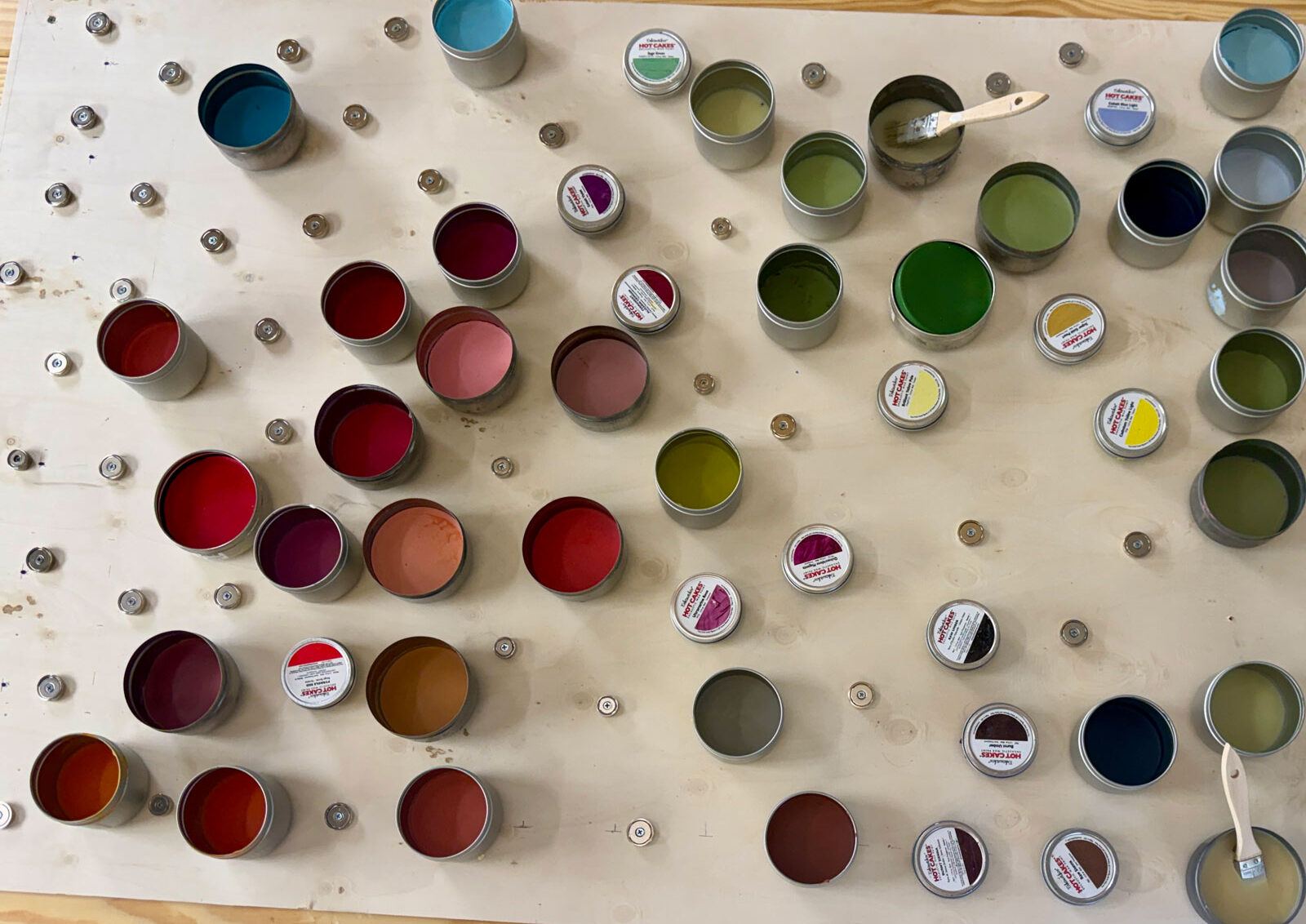 Open tins of colorful encaustic wax paints arranged on Mary's workspace.